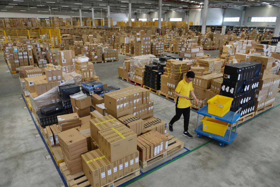 In this Saturday, June 15, 2019, photo, a worker passes by goods piled up at a warehouse in Nan ...