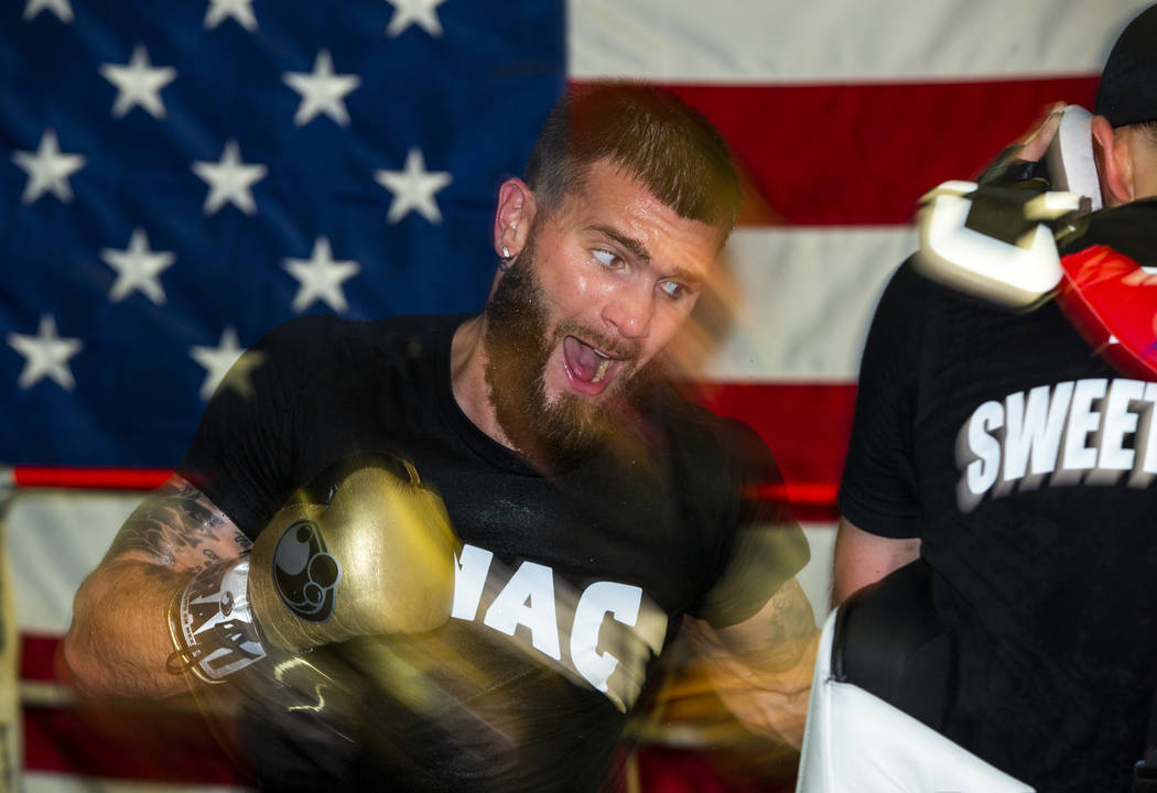 Boxer Caleb Plant, IBF super middleweight champion, left, readies to strike a pad held by train ...