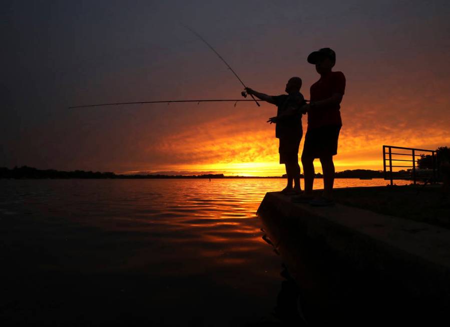 Jon Baucom and his son Connor fish the shores of Lac LaBelle in Oconomowoc, Wis., as the sun se ...