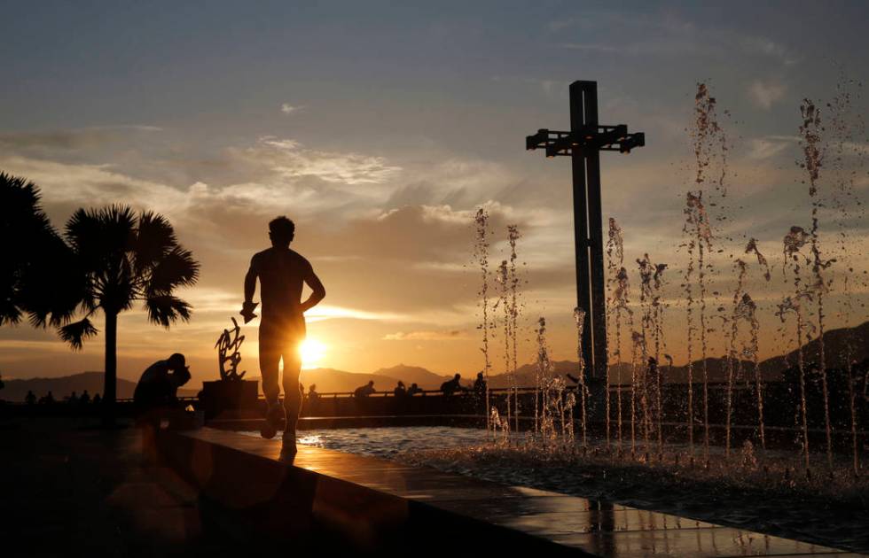 A man runs by a fountain during sunset at the waterfront of Victoria Harbor in Hong Kong, Wedne ...