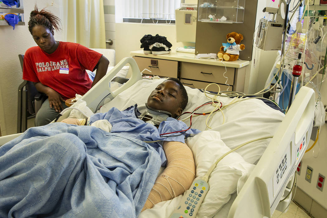 Lennie Modica, 9, sleeps as his mother, Thylicia McKnight, sits beside him on Friday, July 12, ...