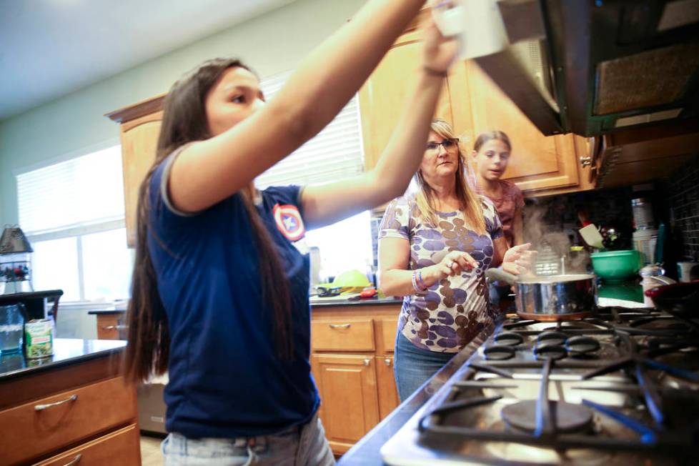 Anita Stephens, center, makes dinner with adopted daughters Serra Stephens, 14, left, and Abi S ...