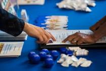 Veronica Arreguin, a personnel analyst with the Clark County School District, left, assists a p ...