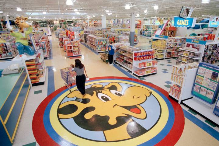 In this July 30, 1996, file photo, a woman pushes a shopping cart over a graphic of Toys R Us m ...