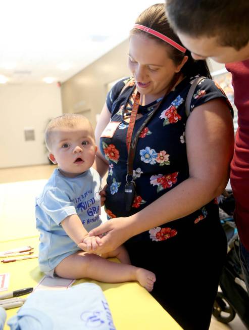 Oakley Martin, 9 months, dons a NICU Grad T-shirt with his parents Brianna and Nathan during th ...