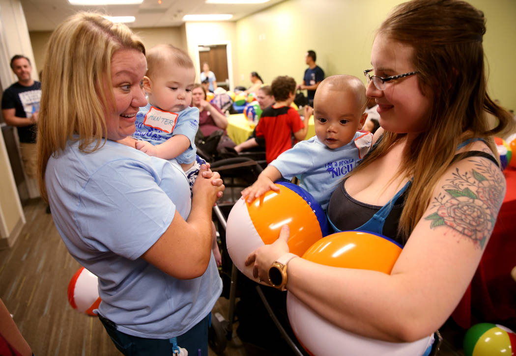 Occupational Therapist Chris Gutierrez, left, with Hunter Graves, 9 months, greets Emily Le and ...