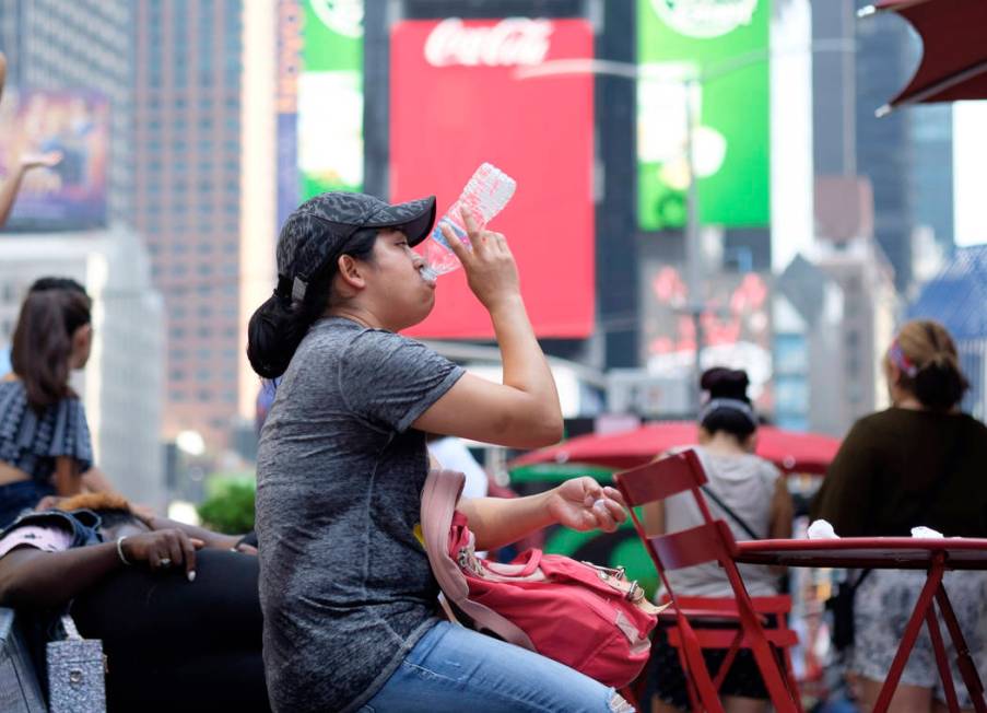 A woman drinks water in Times Square as temperatures reach the mid-to-upper 90s Saturday, July ...