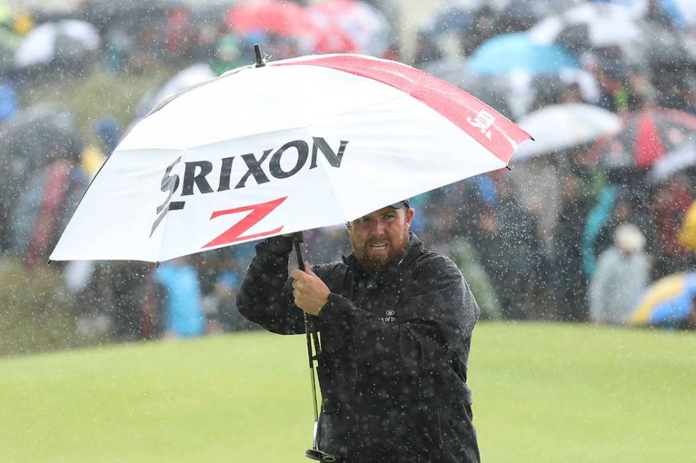 Ireland's Shane Lowry holds an umbrella in heaven rain on the 8th green during the final round ...