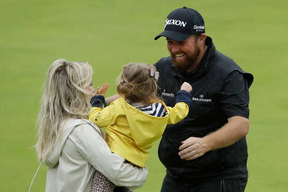 Ireland's Shane Lowry goes to kiss his daughter Iris and hugs his wife Wendy Honner on the 18th ...