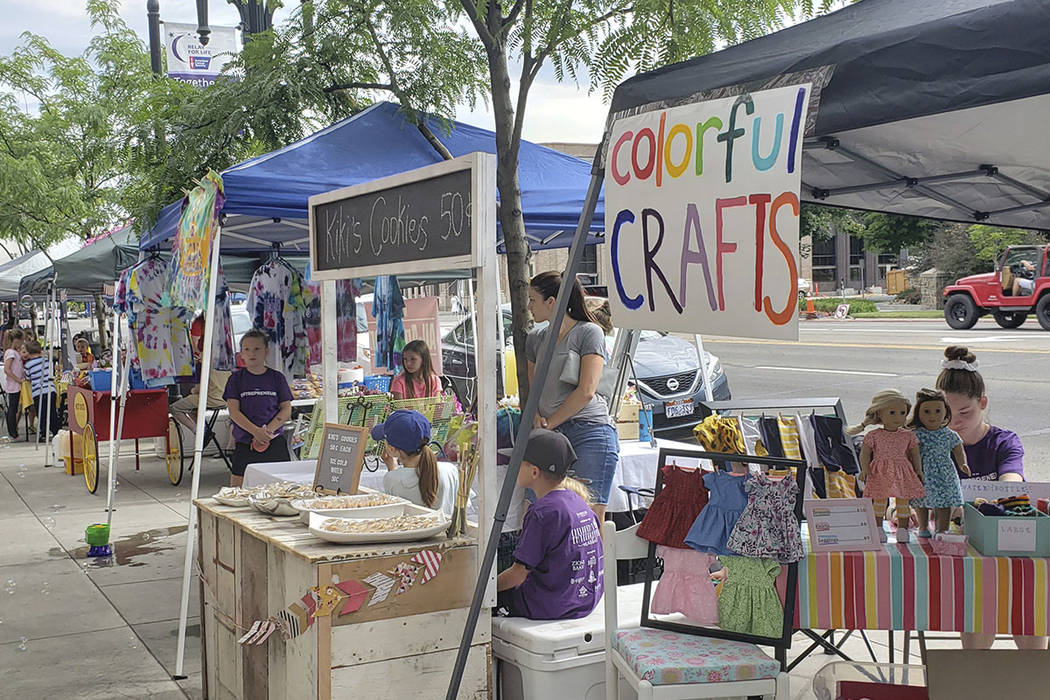 Budding entrepreneurs set up booths on the sidewalk, to sell their products during the Children ...