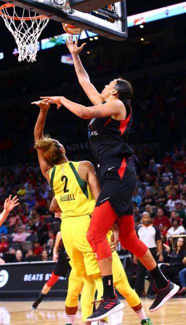 Las Vegas Aces' Liz Cambage, right, lays the ball up past Seattle Storm's Mercedes Russell (2) ...