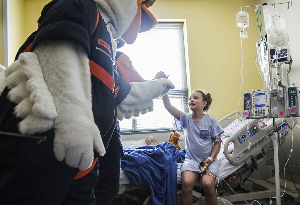 Las Vegas Aviators mascot Spruce the Goose, left, gives Aubrey Blight, 12, a high five at Child ...