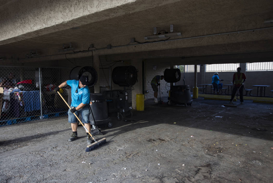 Reese Herrmann sweeps the ground to prepare for bed mats at the Courtyard Homeless Resource Cen ...