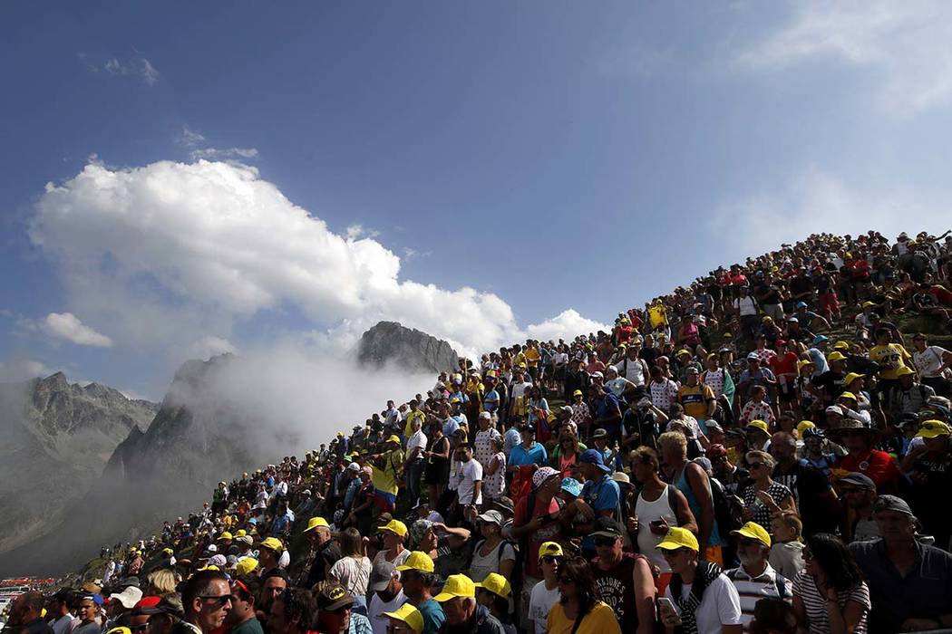 Spectators stand on the Tourmalet pass next to the finish line of the fourteenth stage of the T ...