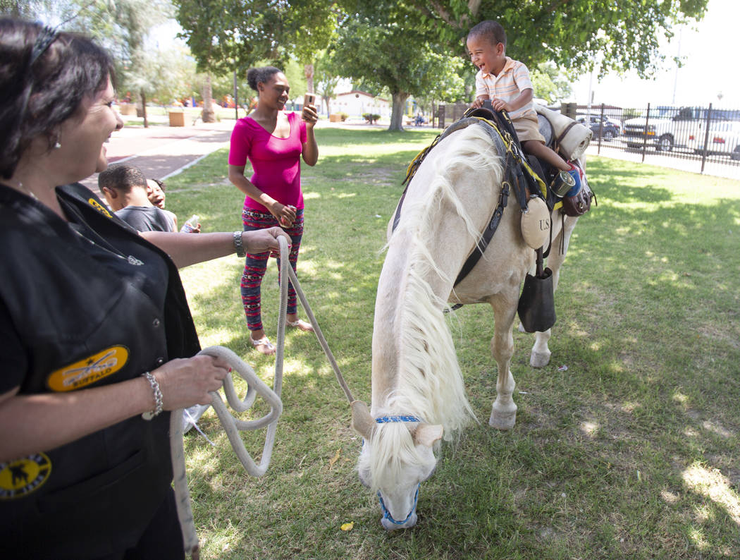 Daviontea Smith, 3, right, rides a horse with the help of Barbie Hill, left, while mother Angel ...