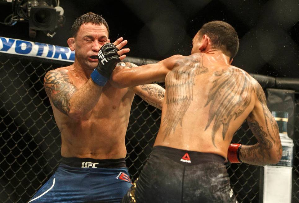 Max Holloway, right, punches Frankie Edgar during a mixed martial arts bout at UFC 240, in Edmo ...