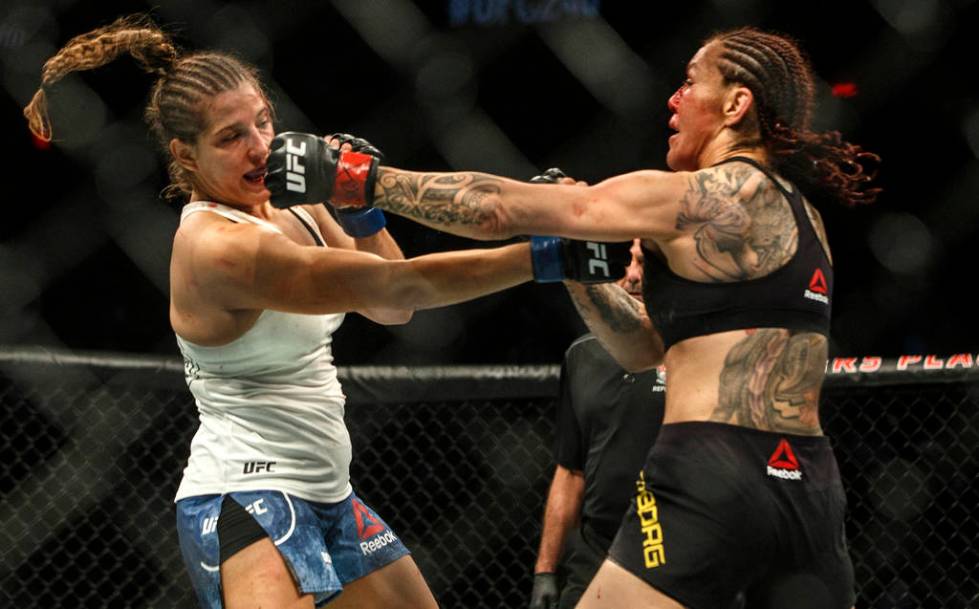 Cris Cyborg, right, hits Felicia Spencer during a mixed martial arts bout at UFC 240, in Edmont ...