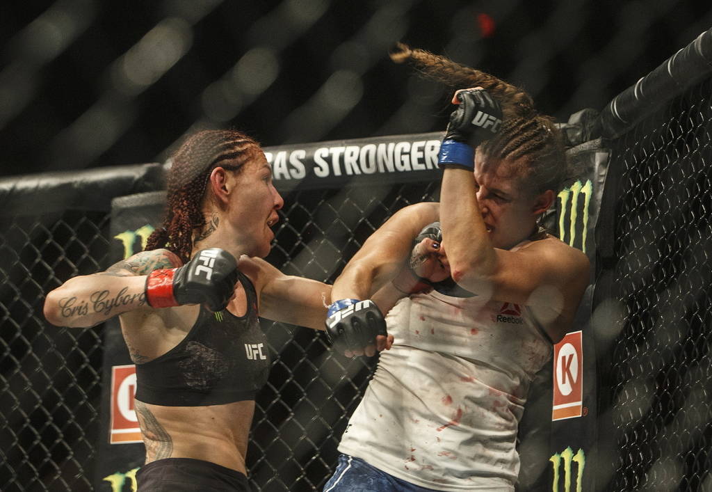 Cris Cyborg, left, hits Felicia Spencer during a mixed martial arts bout at UFC 240, in Edmonto ...