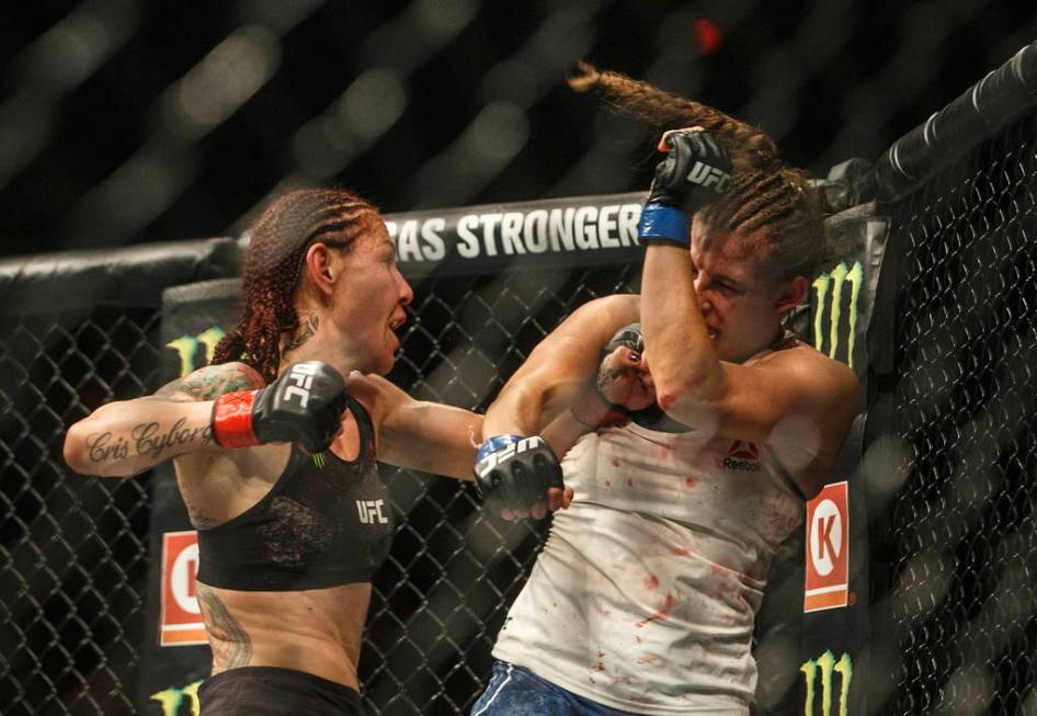 Cris Cyborg, left, hits Felicia Spencer during a mixed martial arts bout at UFC 240, in Edmonto ...