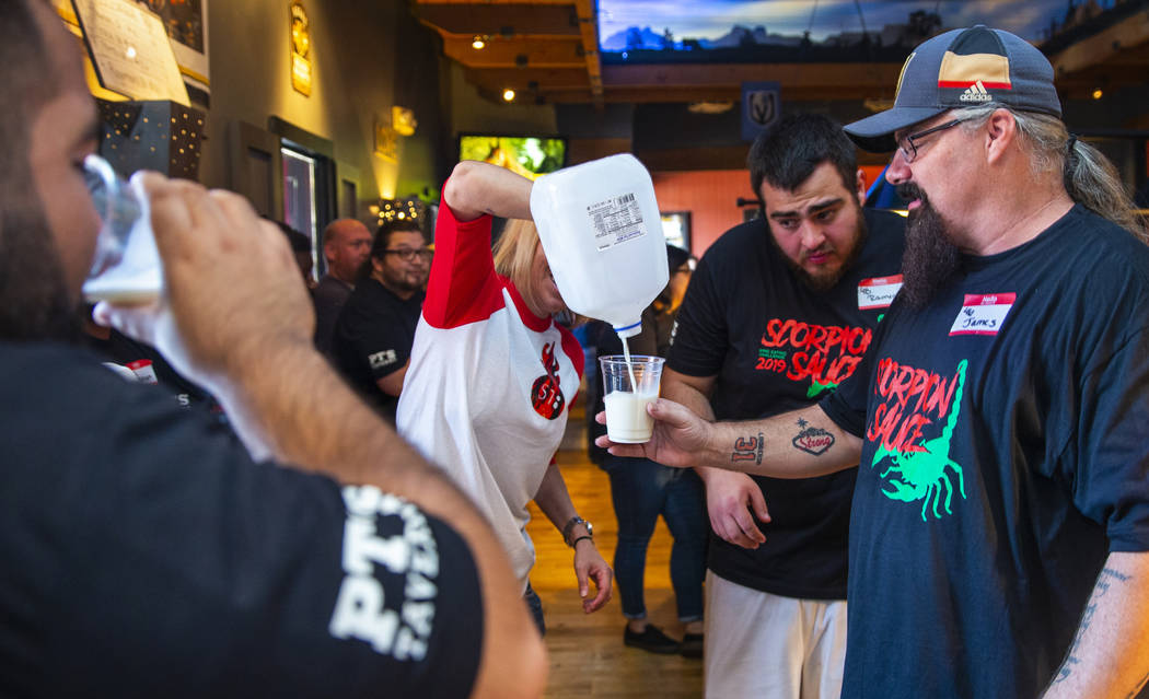 Shannon Goida, center, pours milk for finished competitors using it to cool their mouths off as ...