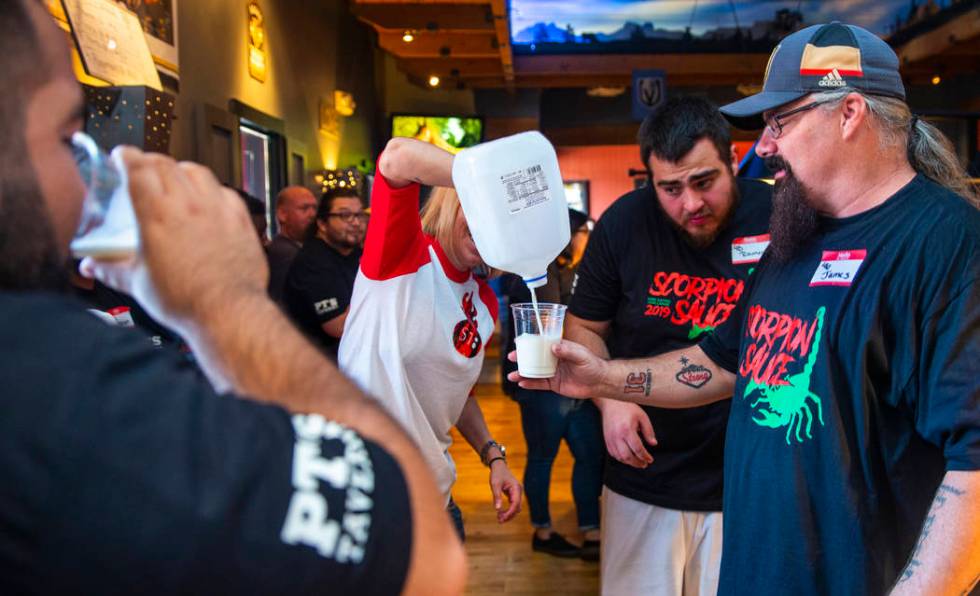 Shannon Goida, center, pours milk for finished competitors using it to cool their mouths off as ...