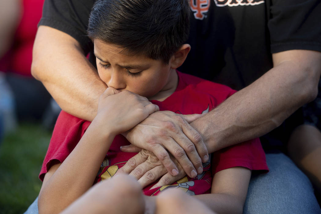 Robbie Ramirez, 10, holds onto his father, Robert Ramirez, during a vigil for victims of a Sund ...