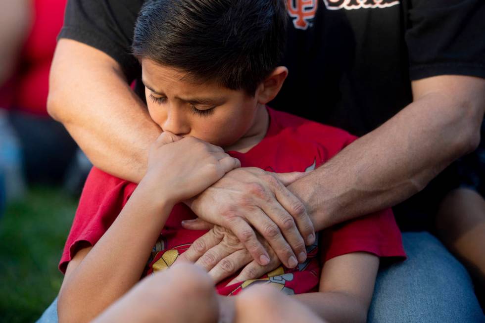 Robbie Ramirez, 10, holds onto his father, Robert Ramirez, during a vigil for victims of a Sund ...