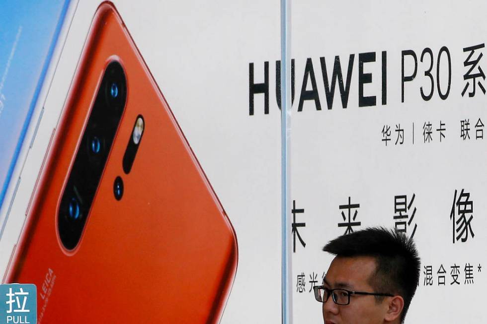 A staffer looks out from a Huawei retail store in Beijing, Tuesday, July 30, 2019. Huawei's glo ...