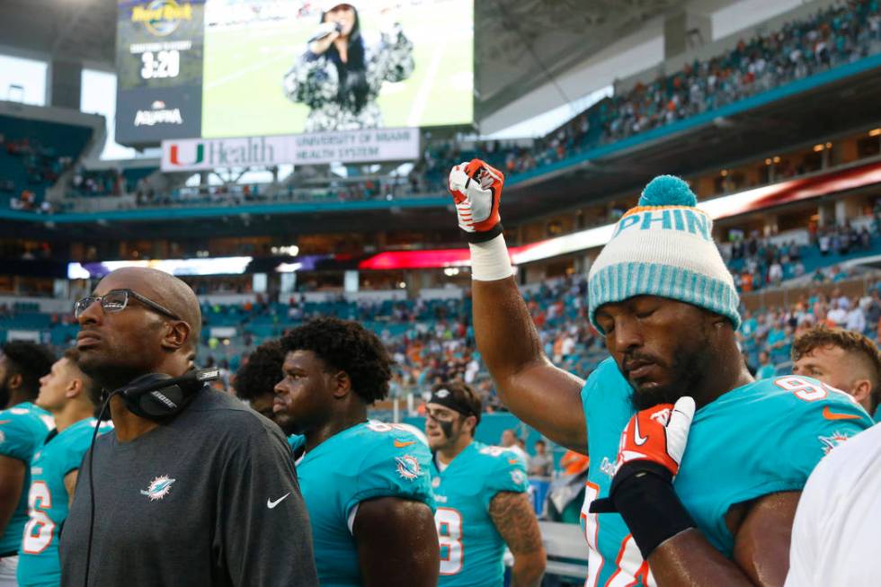 Miami Dolphins defensive end Robert Quinn (94) raises his right fist during the singing of the ...