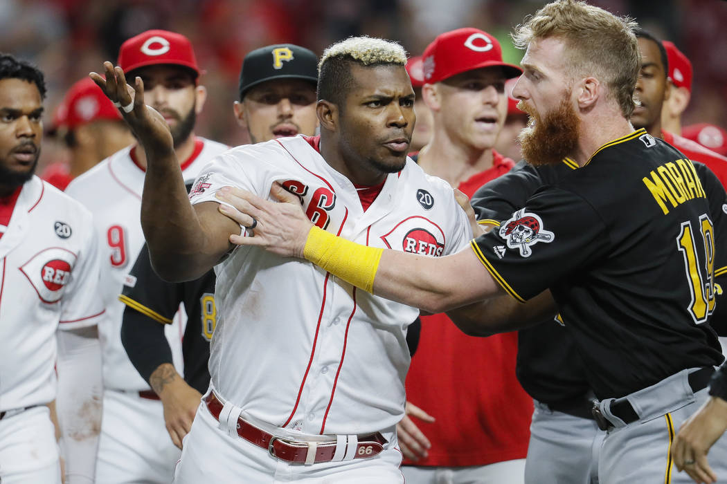 Cincinnati Reds' Yasiel Puig (66) is restrains by Pittsburgh Pirates third baseman Colin Moran ...