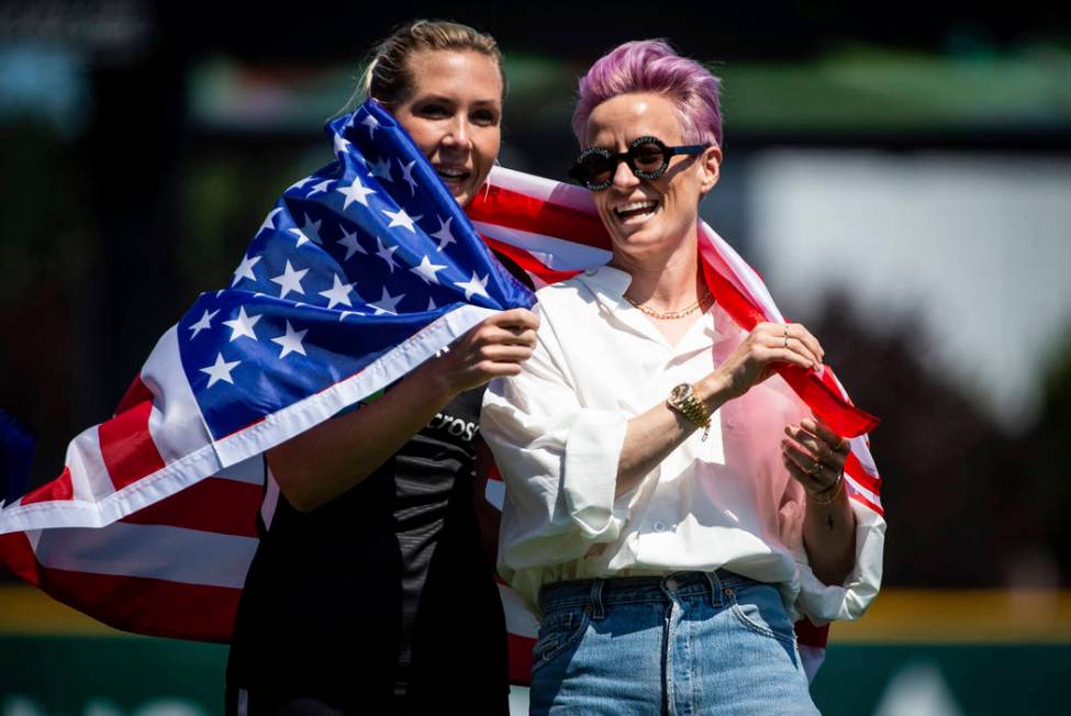 Reign FC midfielder Allie Long, left, and forward Megan Rapinoe, right, wrap themselves in an A ...