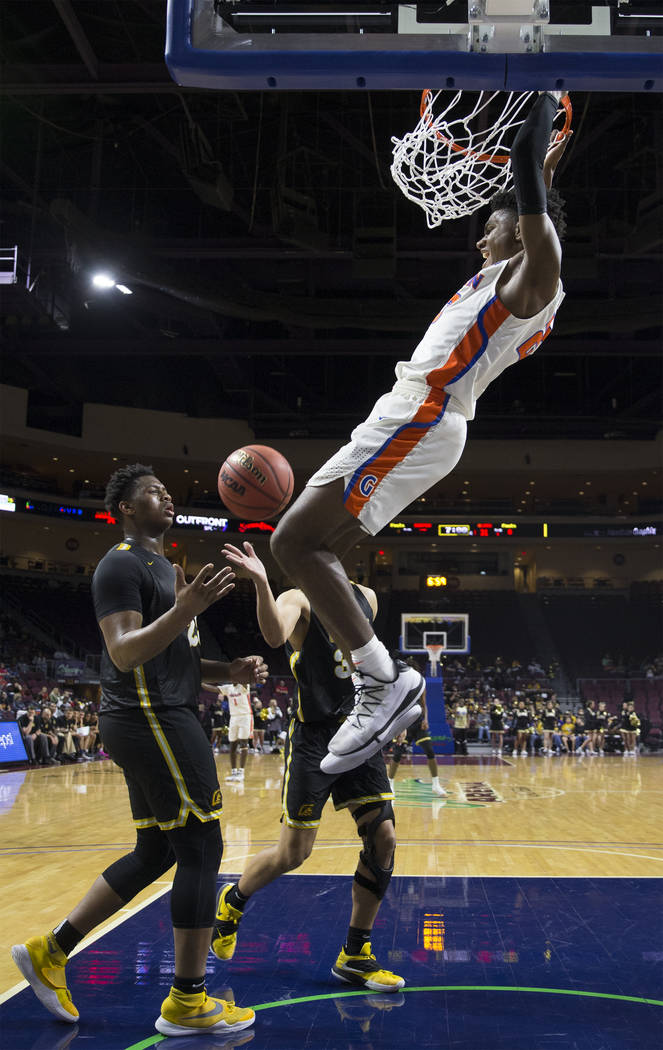 Bishop Gorman junior forward Mwani Wilkinson (23) dunks over Clark senior forward Antwon Jackso ...