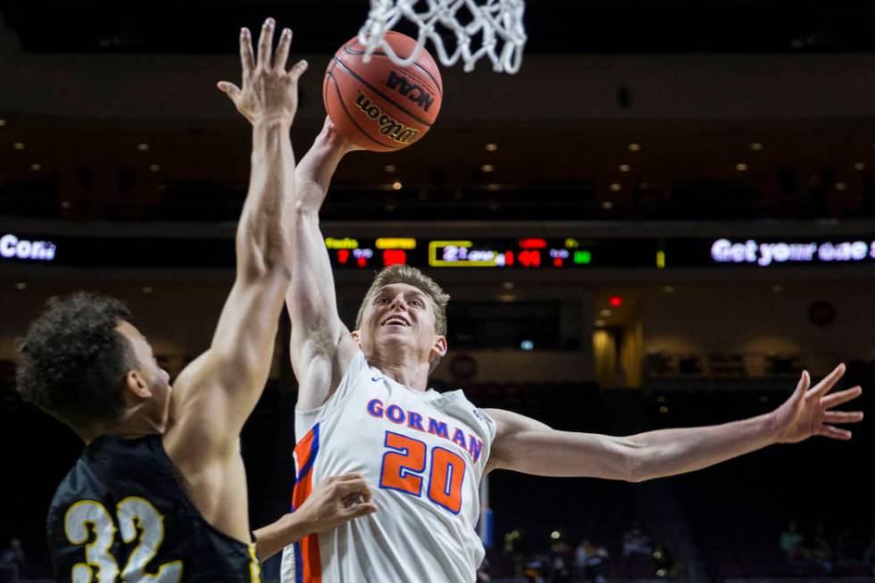 Bishop Gorman junior guard Noah Taitz (20) drives over Clark senior forward Ian Alexander (32) ...