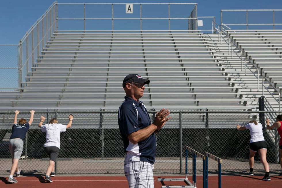 Track and field head coach Rick Teller leads hurdlers in a warm-up during a track and field ...