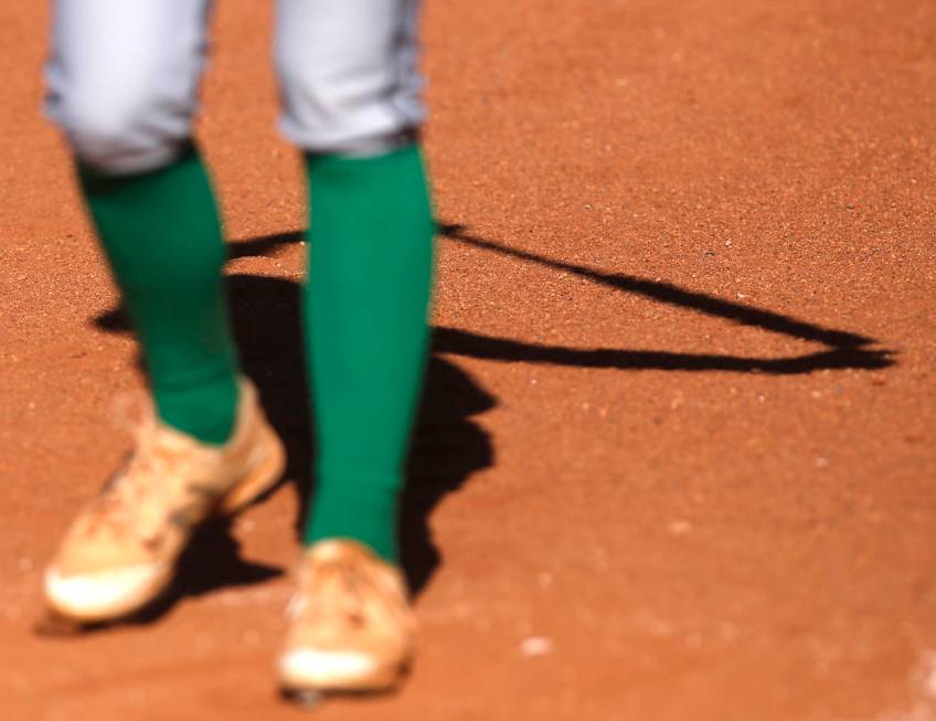 The shadow of a Palo Verde athlete is seen as she stretches before her turn at bat during th ...