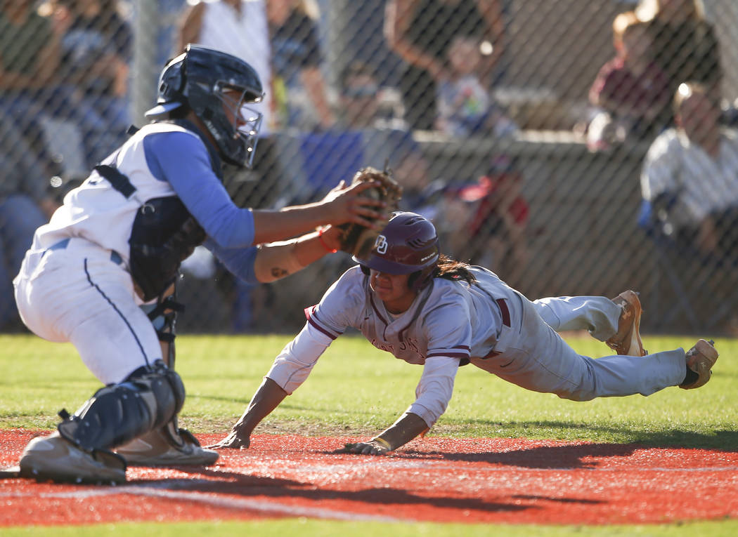 Desert Oasis’ Andrew Martinez nearly scores a run before getting tagged out by Centenn ...