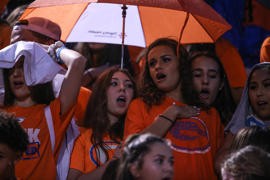 Fans sit in the rain during a delay at the Bishop Gorman versus Miami Central football game ...