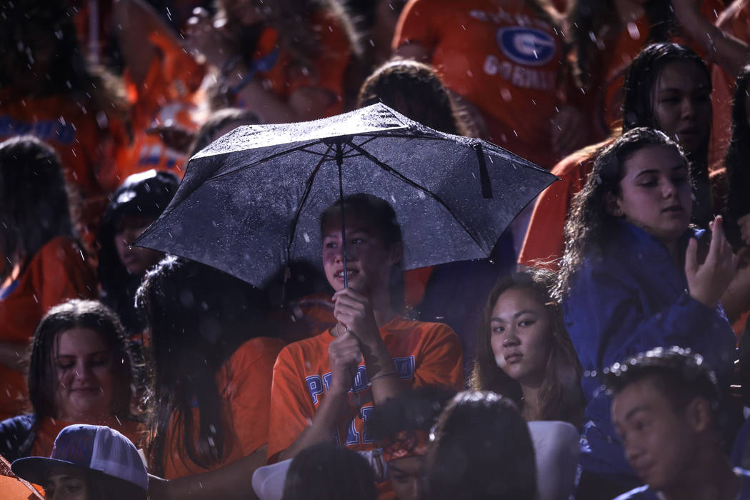 Fans sit in the rain during a delay at the Bishop Gorman versus Miami Central football game ...