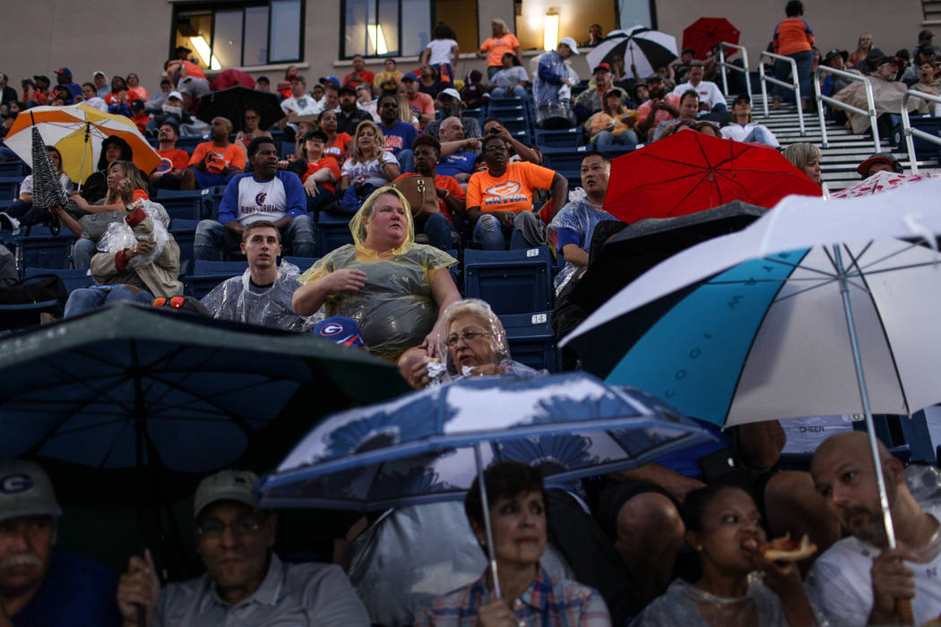 Fans sit in the rain during a delay at the Bishop Gorman versus Miami Central football game ...