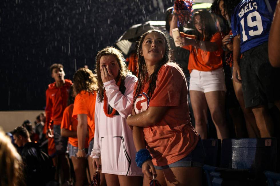 Hope Robertson, right, stands in the rain during a delay at the Bishop Gorman versus Miami C ...