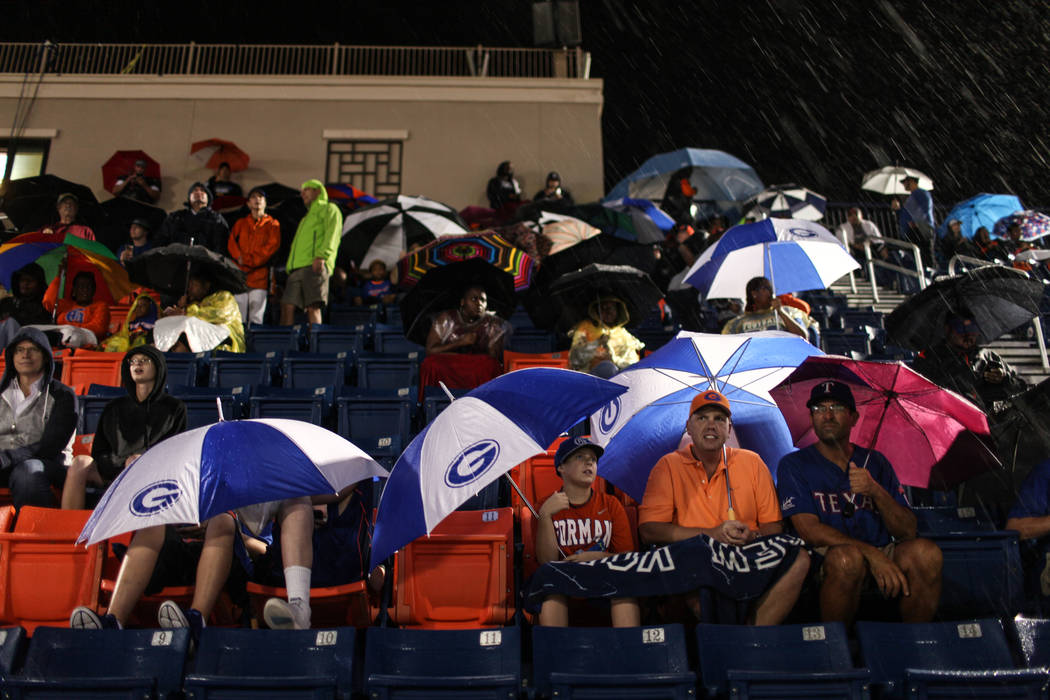 Fans sit in the rain during a delay at the Bishop Gorman versus Miami Central football game ...