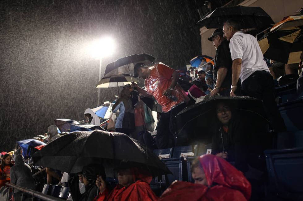 Fans sit in the rain during a delay at the Bishop Gorman versus Miami Central football game ...