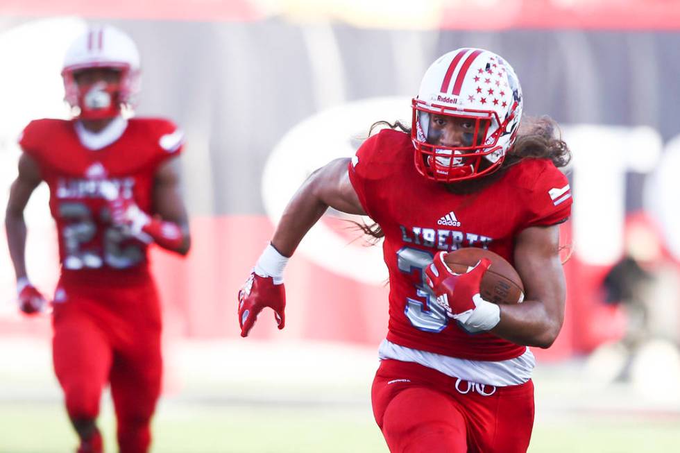 Liberty’s Zyrus Fiaseu (30) heads for the end zone to score a touchdown after intercep ...