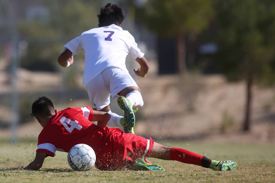 Sunrise Mountain player Joan Cisneros (7) falls over Western player Gustavo Sanchez (4) duri ...