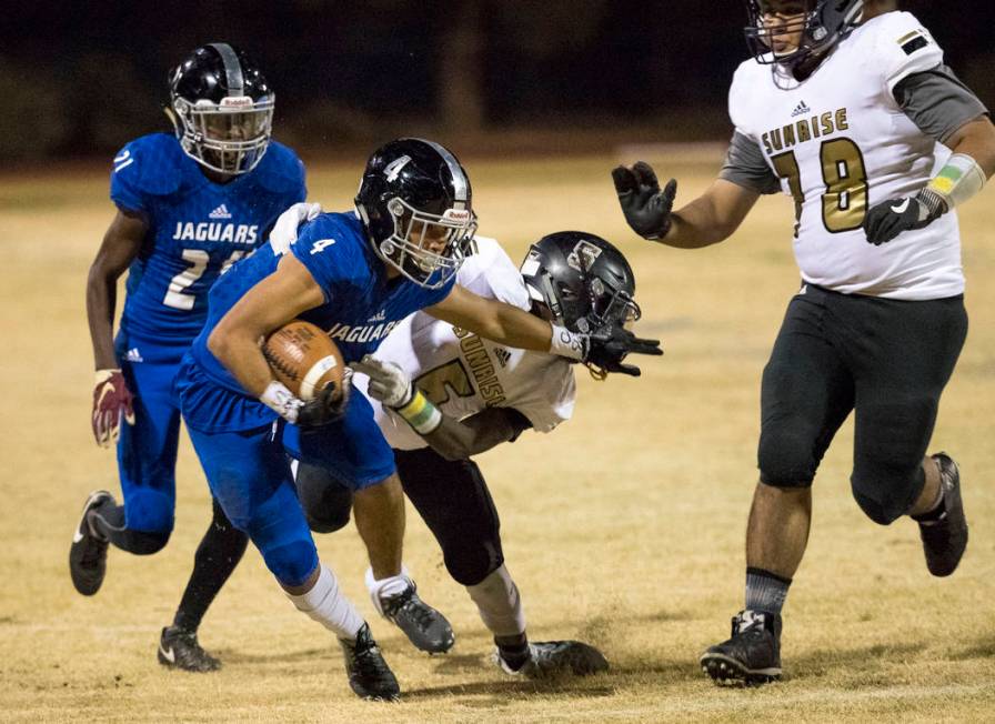 Desert Pines wide receiver Branden Thomas (4) stiff-arms Sunrise Mountain defender Xavier Ky ...