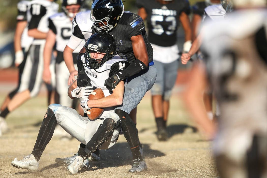 Spring Creek’s Dakota Larson (4), left, is tackled by Desert Pines’ Branden Thom ...