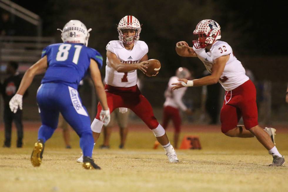 Liberty quarter back Kenyon Oblad (7) hands the ball off to Kyle Beaudry (32) during the fir ...