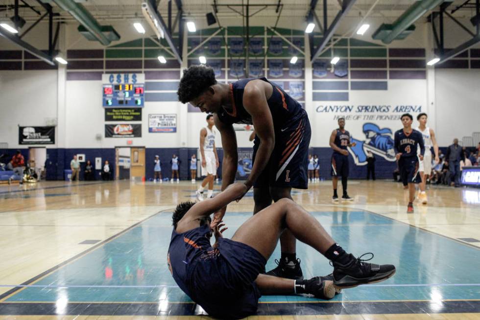 Legacyճ Cristian Pitts (3), left, is helped up by teammate Chris White (5), right, aft ...