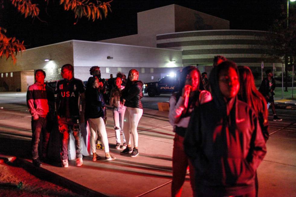 Students stand nearby after officers cleared an area using pepper spray to break up a fight ...