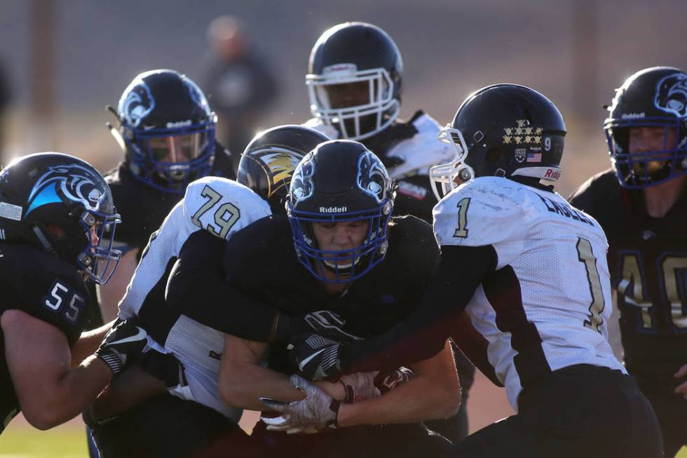 Spring Mountain players attempt to take down Pahranagat Valley player Richard Lewis (19) dur ...